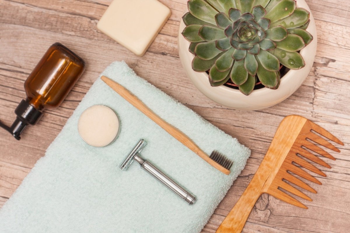 Zero waste bathroom items with a metal safety razor, bamboo toothbrush and wooden comb on a towel
