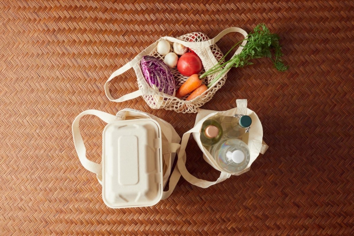Reusable mesh and cotton bags with vegetables, jars and a food container