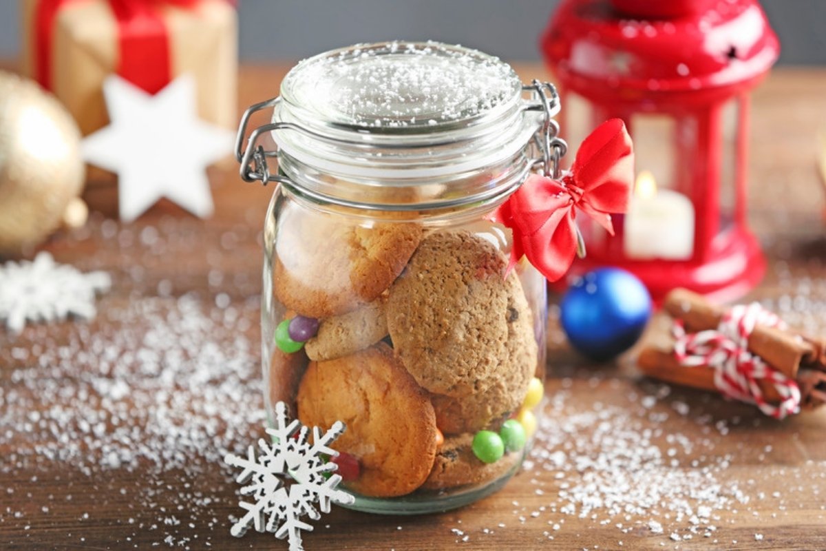Glass jar filled with homemade cookies and tied with a red bow as a Christmas gift